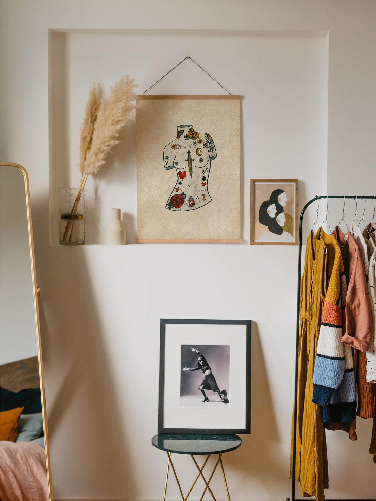 an illustrated art print of a tattooed torso statue. it is filled with decorative motifs over a textured light yellow background. it is in a room and is hung up on the wall.