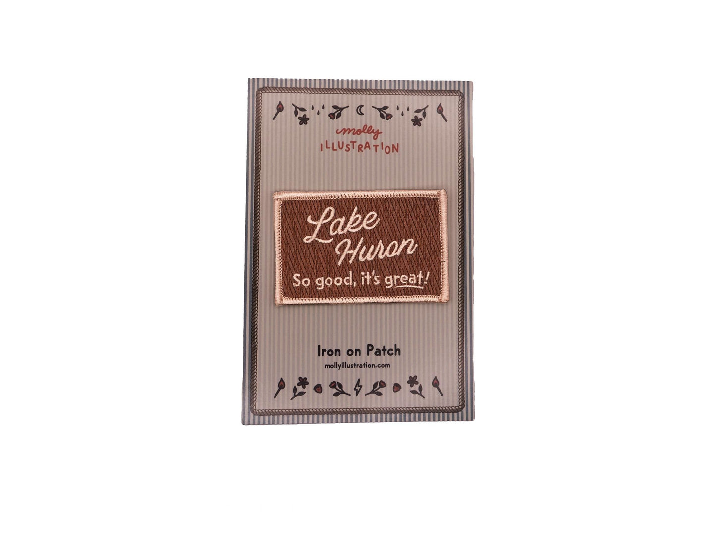 a brown rectangular embroidered iron on patch that reads "Lake Huron, So good, it's great!" in off white lettering packaged on a striped Molly Illustration backer card