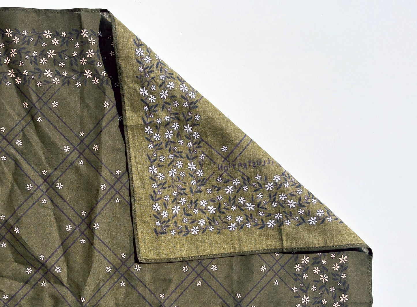 An olive green cotton bandana with white floral design, folded to show both the plain and printed sides against a white background.