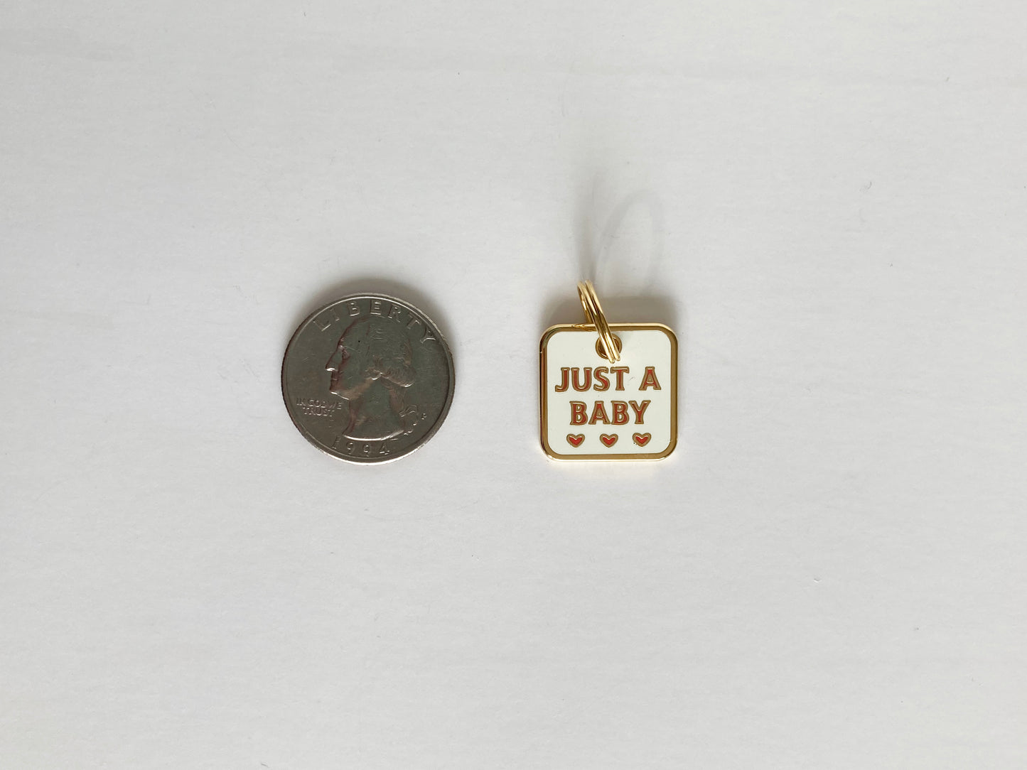 A hard enamel pet collar charm that reads “Just a Baby.”