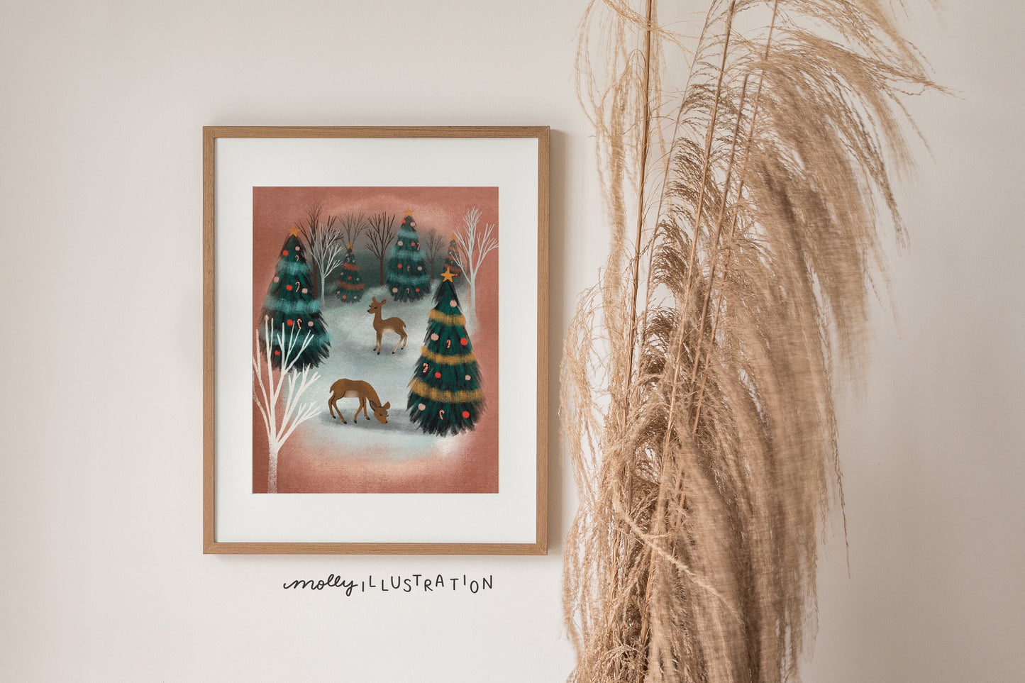 A mid century inspired art print of a snowy christmas forest scene. There are two deer standing among many pine trees that are decorated with garlands and ornaments.