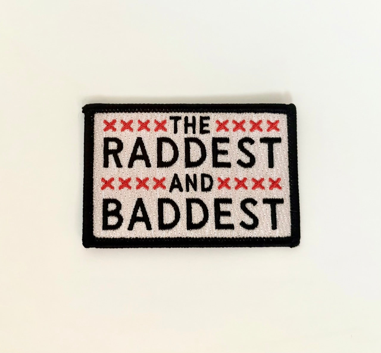 An embroidered iron on patch that reads the raddest and the baddest