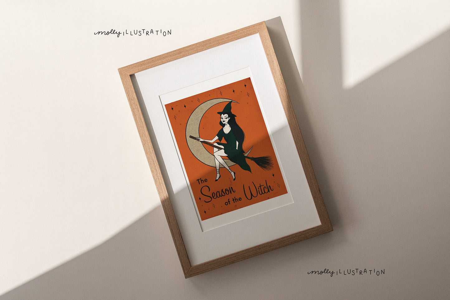 an illustrated art print of a cartoon witch riding a broom in front of a present moon. the bottom reads the season of the witch