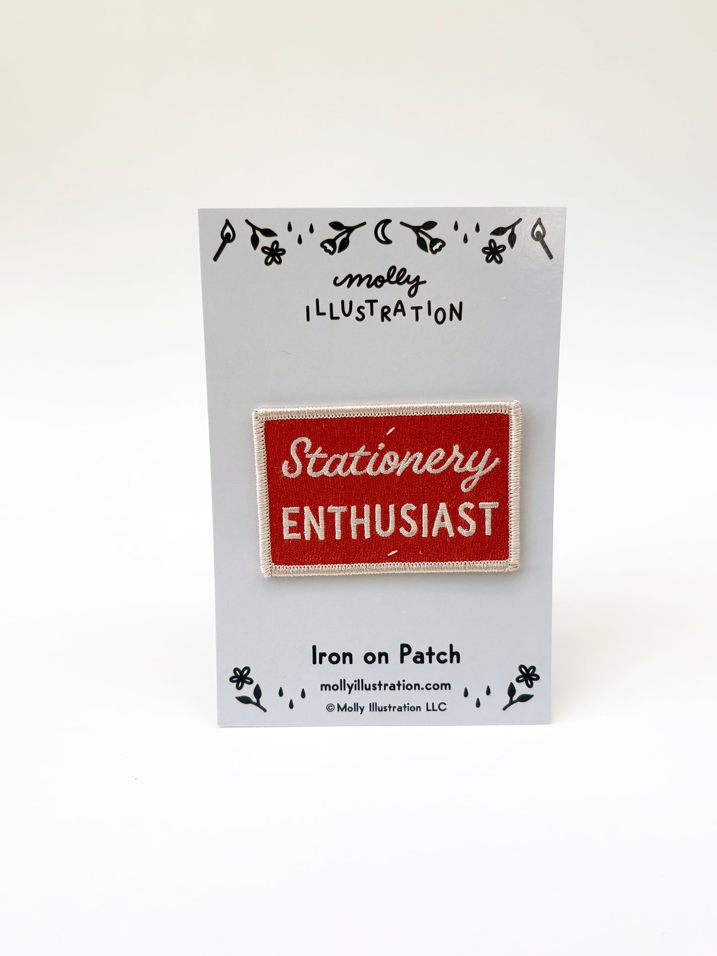 Iron on patch with 'Stationery Enthusiast' text on a Molly Illustration branded card.