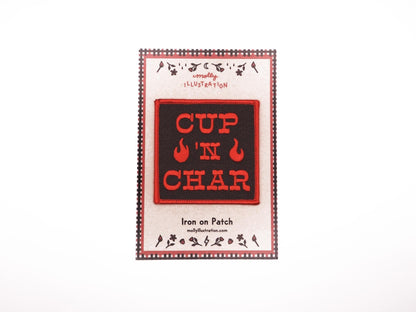 A black square embroidered iron on patch that reads "CUP 'N CHAR" in red letters. there are two red flames beside the "'N" and there is a red merrowed border. it is placed on top of a Molly Illustration backer card.