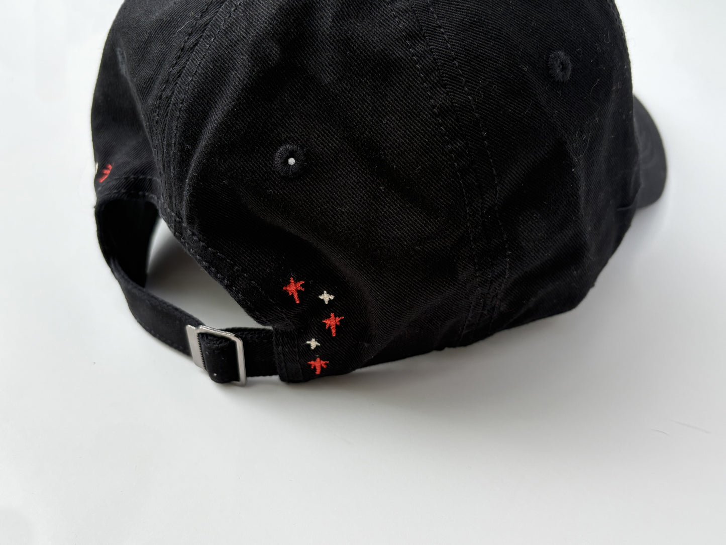 Black cap with red and white embroidered details on a white background