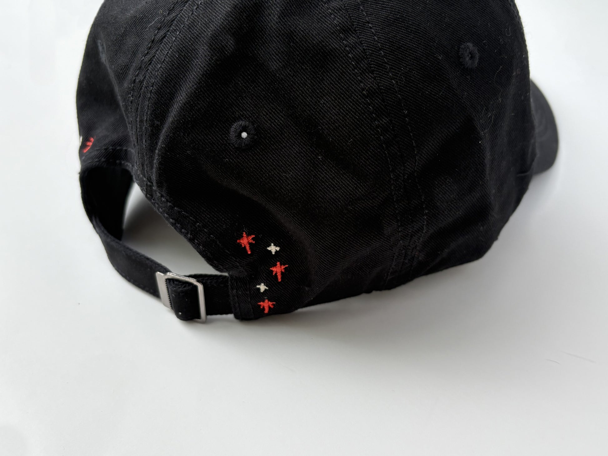 Black cap with red and white embroidered details on a white background