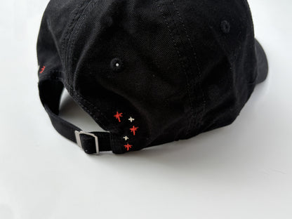Black cap with red and white embroidered details on a white background