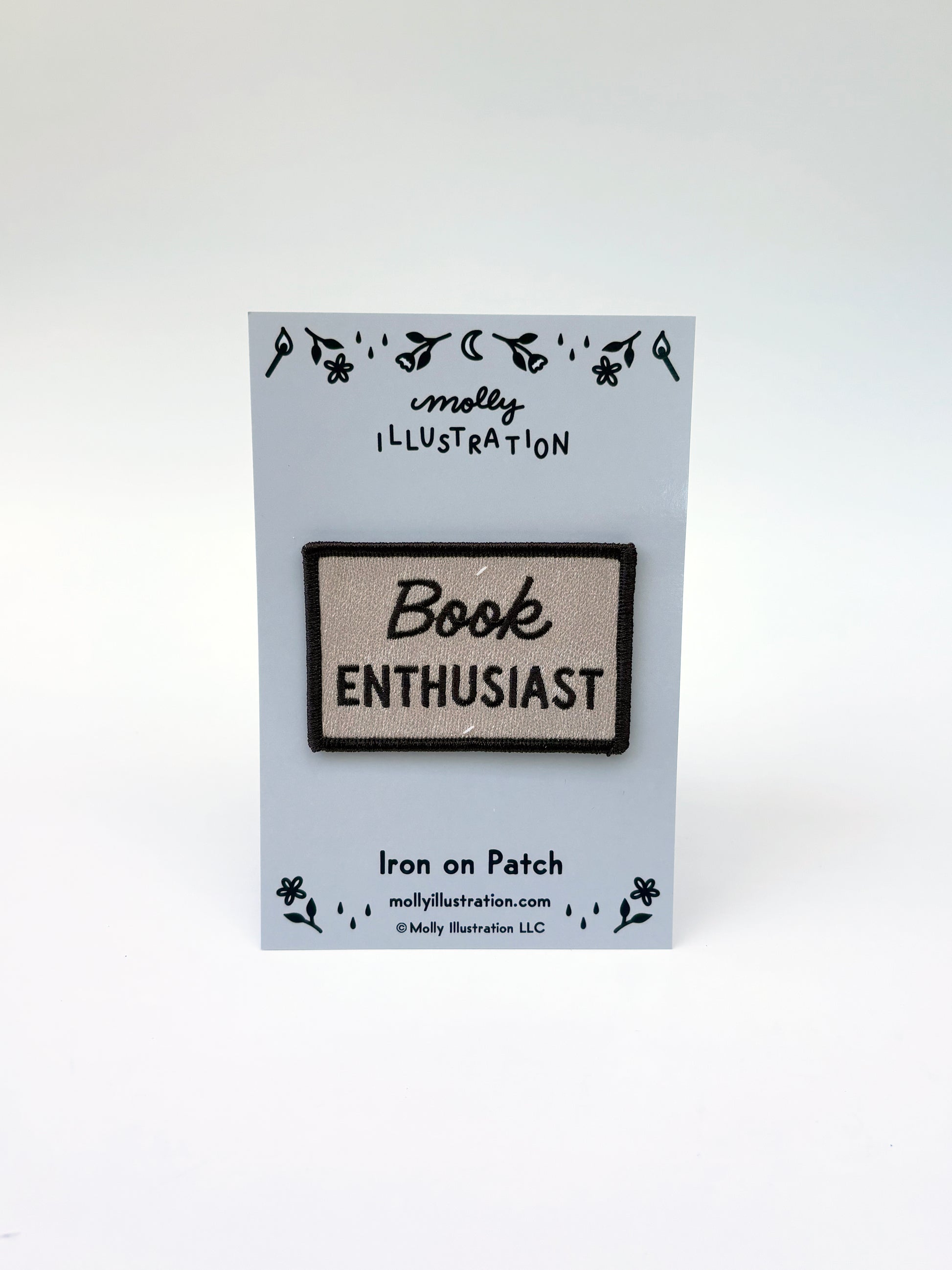 Iron on patch with 'Book Enthusiast' text on a clear card with branding.