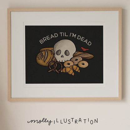 An illustrated art print of various cartoon breads and pastries with a skull sitting on top of them. A small red bird sits nearby and is eating a loaf of bread. Above it reads “Bread til I’m Dead.”