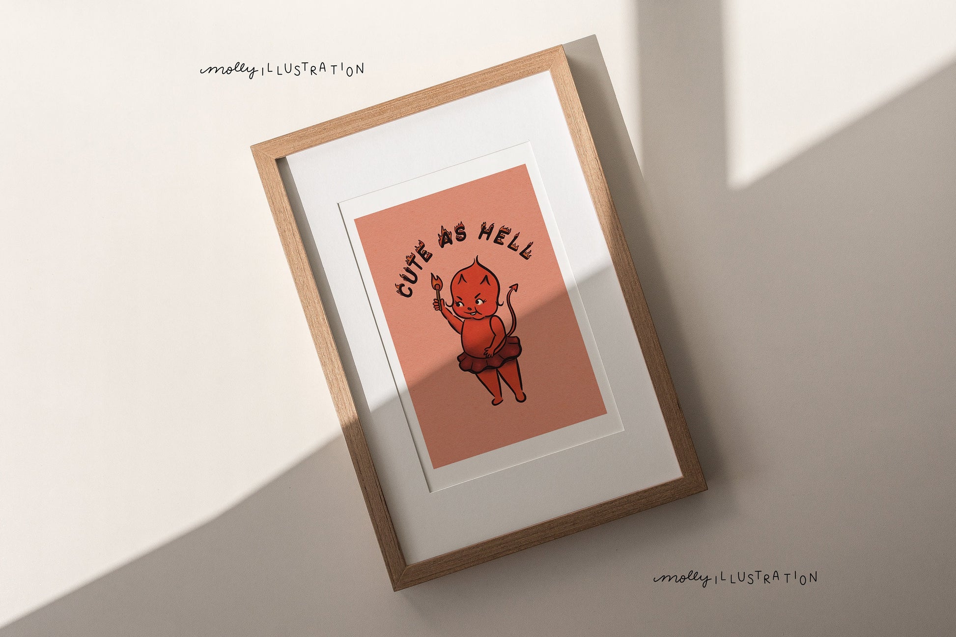 an illustrated art print of a cartoon red devil baby in a tutu lighting the phrase "cute as hell" on fire with a match