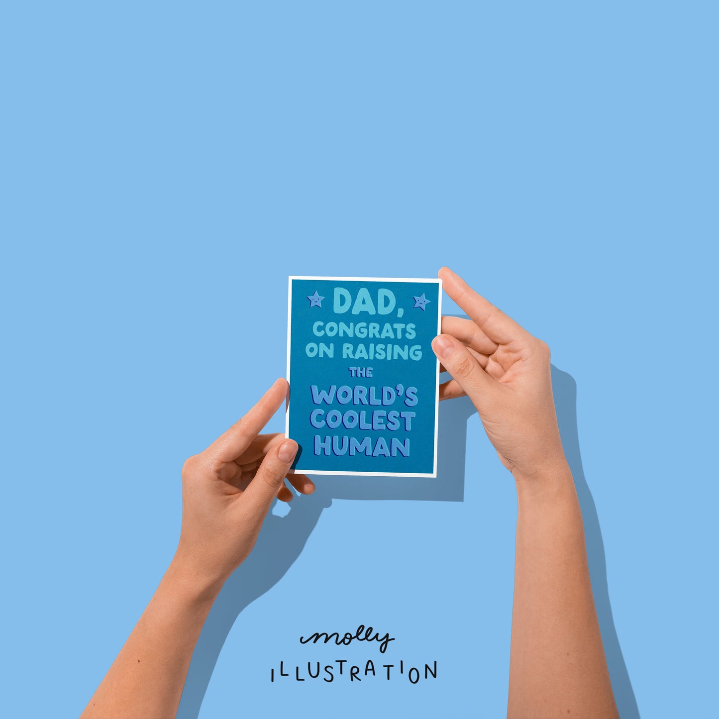 a vertical greeting card being held that reads "dad, congrats on raising the world's coolest human"