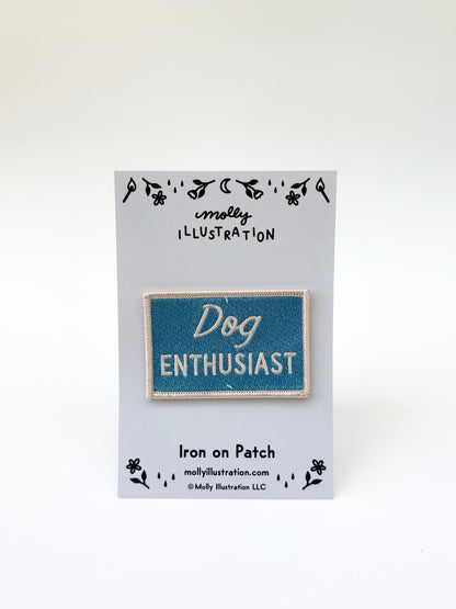 Iron on patch labeled 'Dog Enthusiast' on a gray card with 'molly illustration' branding.