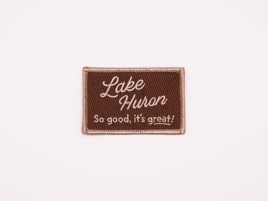 a brown rectangular embroidered iron on patch that reads "Lake Huron, So good, it's great!" in off white lettering.