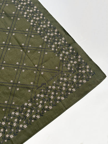 An olive green square scarf with a dark green grid pattern and a border of small white flowers, laid flat on a white surface.