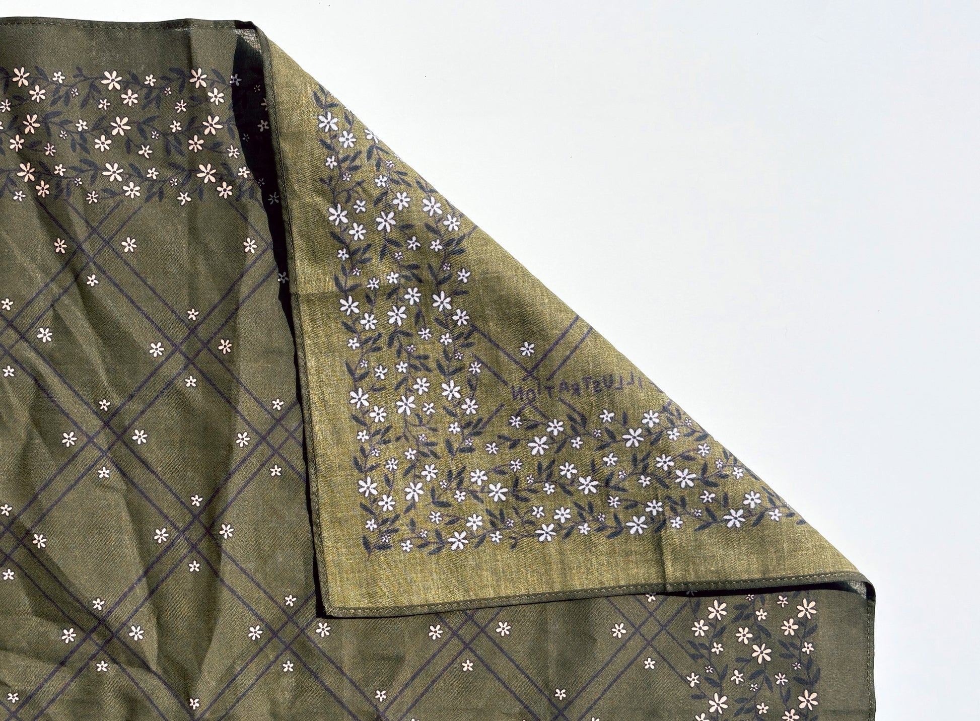 An olive green cotton bandana with white floral design, folded to show both the plain and printed sides against a white background.
