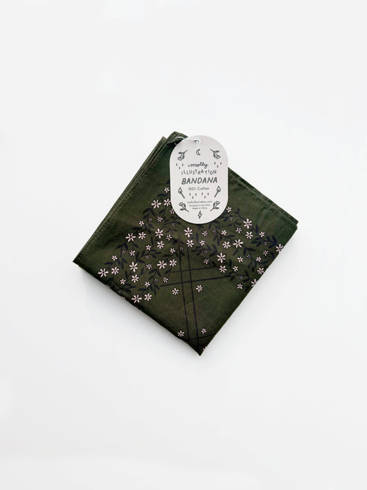 A green cotton bandana with a black grid pattern and small white floral motifs, folded with its white paper tag attached, on a clean white background.