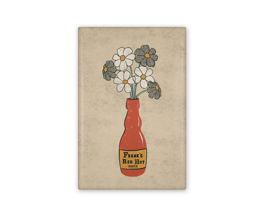 a rectangular illustrated refrigerator magnet of a frank's red hot sauce bottle that has daisies in it.