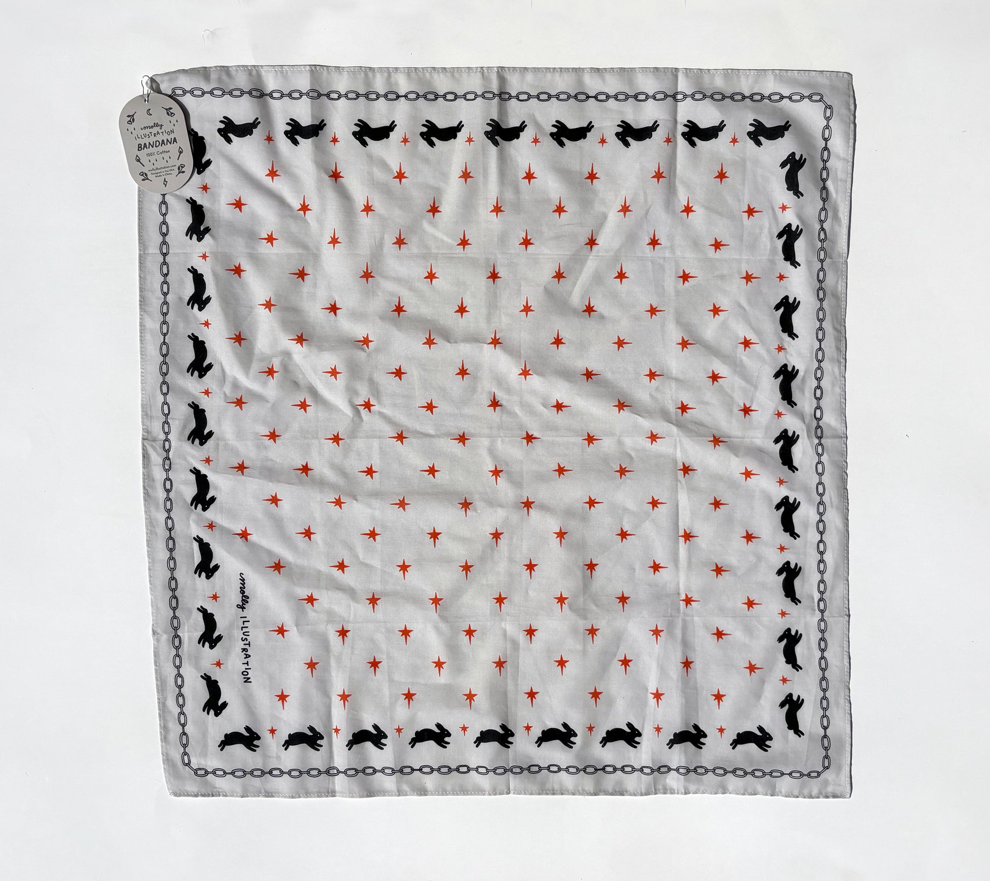 A square white scarf with a repeating pattern of small red stars, black rabbit silhouettes, and a black chain border, laid flat on a white background with a hanging tag.