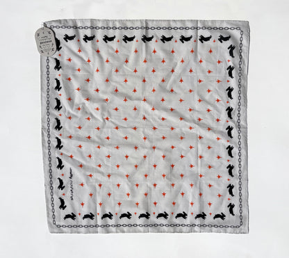 A square white scarf with a repeating pattern of small red stars, black rabbit silhouettes, and a black chain border, laid flat on a white background with a hanging tag.