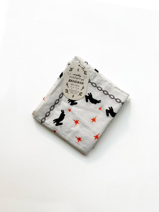 A folded white cotton bandana featuring a black rabbit and chain pattern with small red star accents, complete with a paper hangtag.
