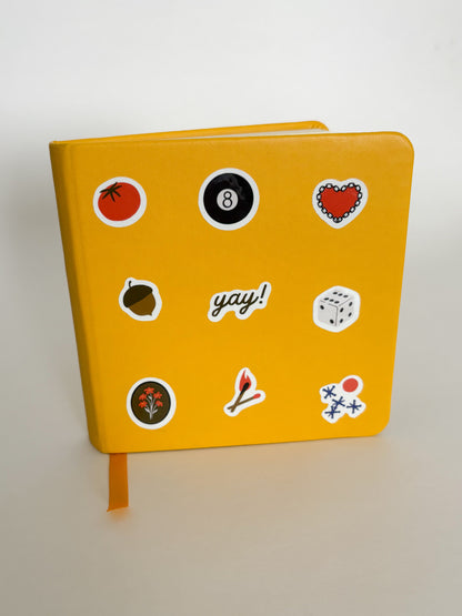 Yellow notebook with various stickers on a white background