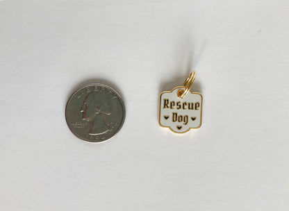 A hard enamel pet collar charm that reads “Rescue Dog” next to a quarter.