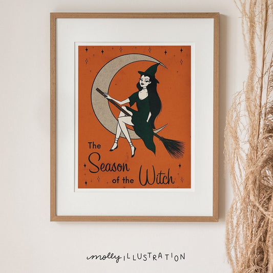 an illustrated art print of a cartoon witch riding a broom in front of a present moon. the bottom reads the season of the witch