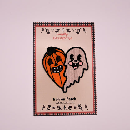 a heart shaped embroidered iron on patch that is one half jack o lantern and one half ghost packaged on a Molly illustration backer card.