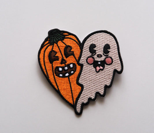 a heart shaped embroidered iron on patch that is one half jack o lantern and one half ghost.