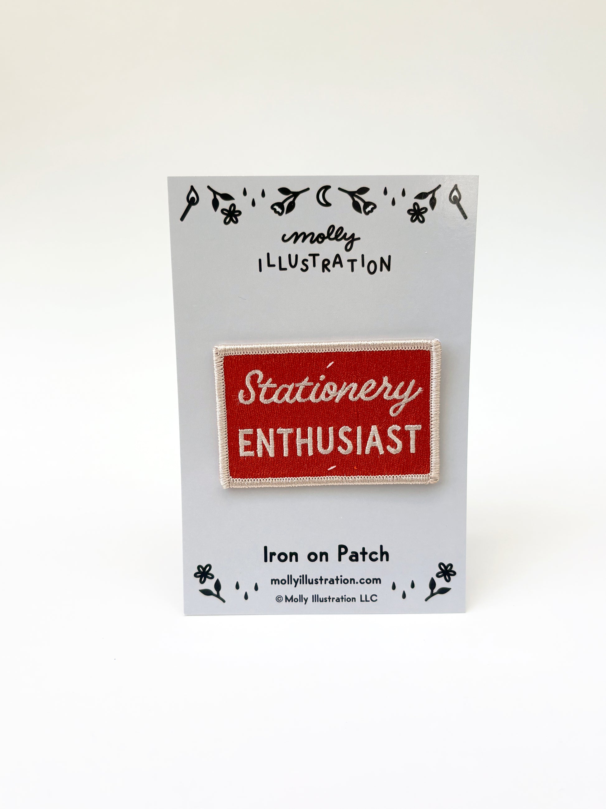 Iron on patch with 'Stationery Enthusiast' text on a Molly Illustration branded card.