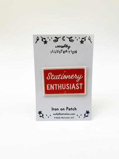 Iron on patch with 'Stationery Enthusiast' text on a Molly Illustration branded card.