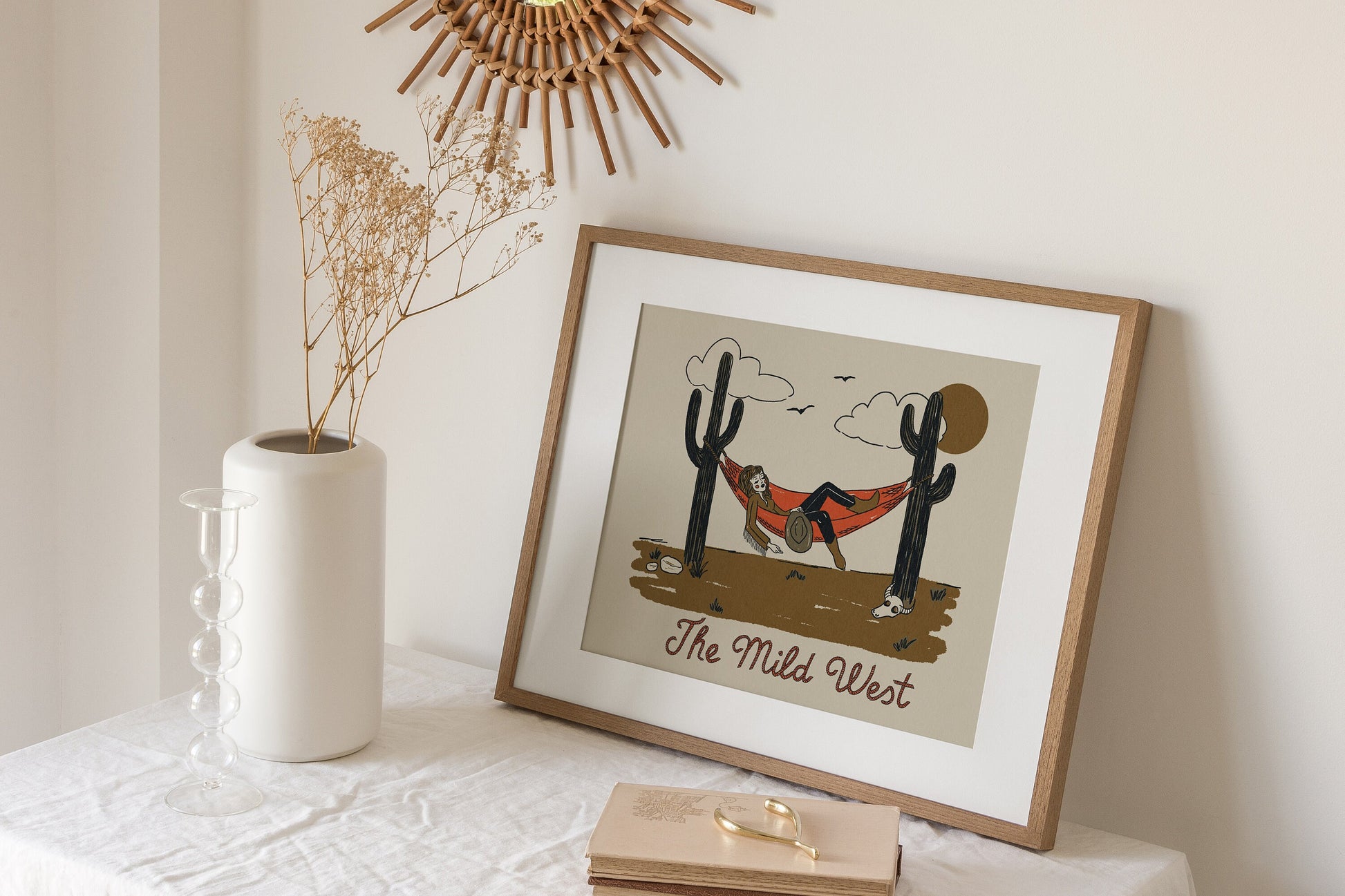 a vintage inspired illustrated art print of a cartoon cowgirl napping in a hammock hung between two cacti. Beneath this reads "The Mild West."