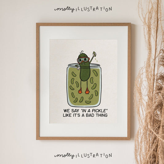 a white and green illustrated art print of a pickle swimming in a pickle jar that reads "We say in a pickle like it's a bad thing.”