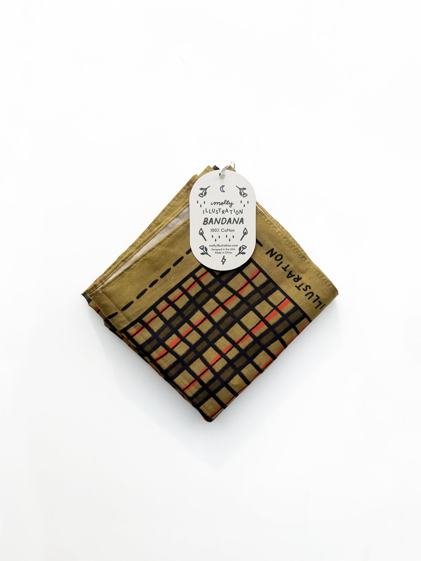 A folded cotton bandana with a plaid pattern in black, beige, and orange-red, featuring a gold-brown border and a white paper hangtag.